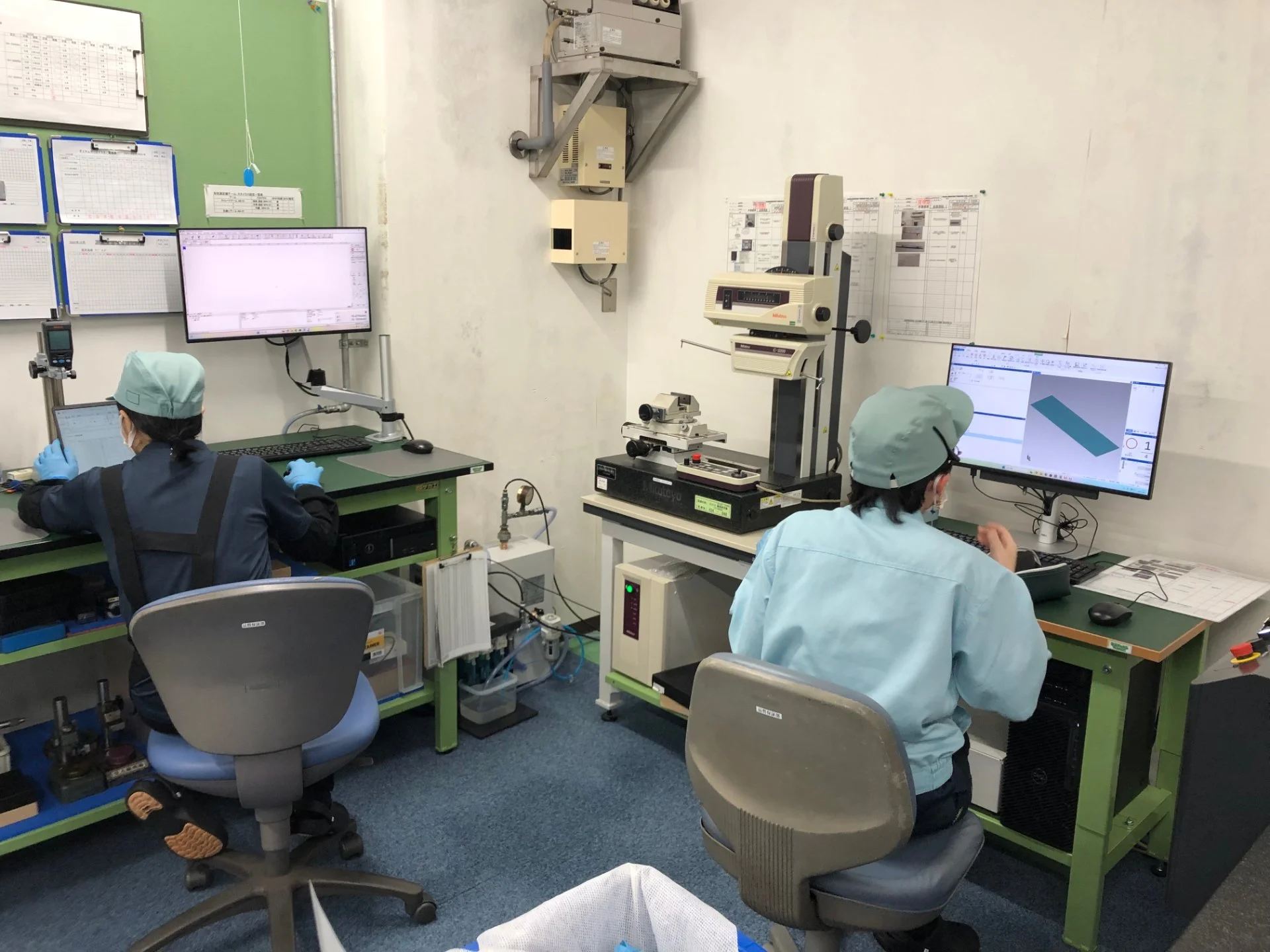 測定機器とパソコンを使って部品の寸法を確認する検査担当者